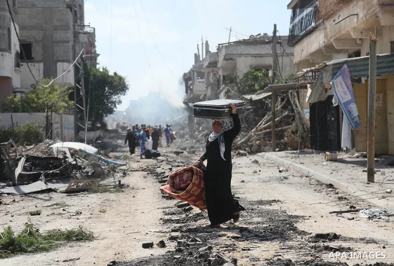 A Palestinian woman carries her belongings from her destroyed house in the northern district of Beit Hanun in the Gaza Strip during an humanitarian truce on July 26, 2014. The bodies of at least another 35 Palestinians w...