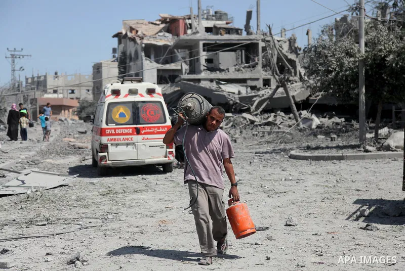 A Palestinian man carries his belongings from her destroyed house in the northern district of Beit Hanun in the Gaza Strip during an humanitarian truce on July 26, 2014. The bodies of at least another 35 Palestinians wer...