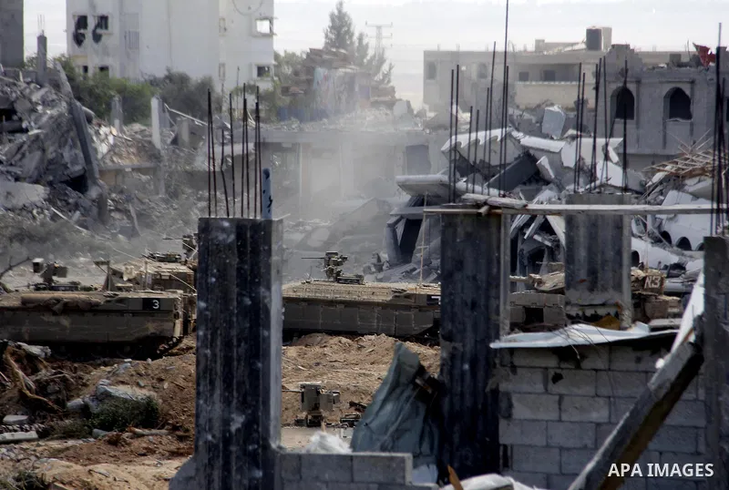 An Israeli military tank patrols amid of rubble of destroyed buildings at al-Shijaiyah district in the eastern Gaza City on July 26, 2014. Israeli troops remained in place across the Gaza Strip and continued to search fo...
