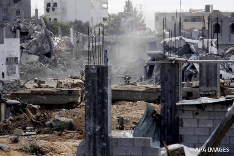 An Israeli military tank patrols amid of rubble of destroyed buildings at al-Shijaiyah district in the eastern Gaza City on July 26, 2014. Israeli troops remained in place across the Gaza Strip and continued to search fo...