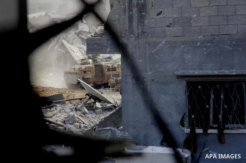 An Israeli military tank patrols amid of rubble of destroyed buildings at al-Shijaiyah district in the eastern Gaza City on July 26, 2014. Israeli troops remained in place across the Gaza Strip and continued to search fo...