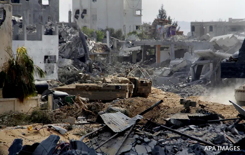 An Israeli military tank patrols amid of rubble of destroyed buildings at al-Shijaiyah district in the eastern Gaza City on July 26, 2014. Israeli troops remained in place across the Gaza Strip and continued to search fo...