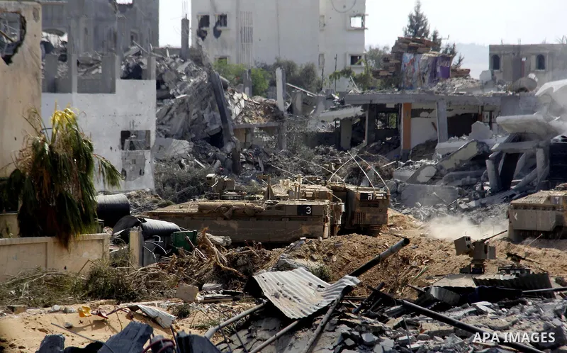 An Israeli military tank patrols amid of rubble of destroyed buildings at al-Shijaiyah district in the eastern Gaza City on July 26, 2014. Israeli troops remained in place across the Gaza Strip and continued to search fo...