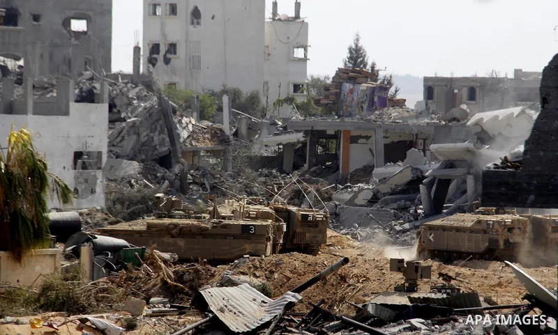 An Israeli military tank patrols amid of rubble of destroyed buildings at al-Shijaiyah district in the eastern Gaza City on July 26, 2014. Israeli troops remained in place across the Gaza Strip and continued to search fo...