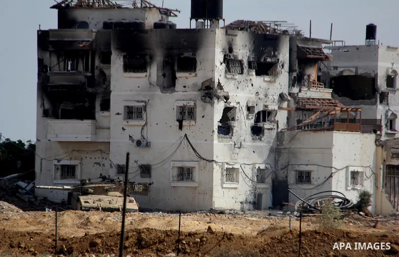 An Israeli military tank patrols amid of rubble of destroyed buildings at al-Shijaiyah district in the eastern Gaza City on July 26, 2014. Israeli troops remained in place across the Gaza Strip and continued to search fo...