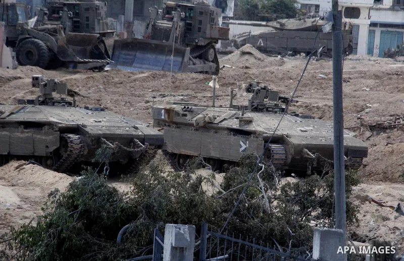 An Israeli military tank patrols amid of rubble of destroyed buildings at al-Shijaiyah district in the eastern Gaza City on July 26, 2014. Israeli troops remained in place across the Gaza Strip and continued to search fo...