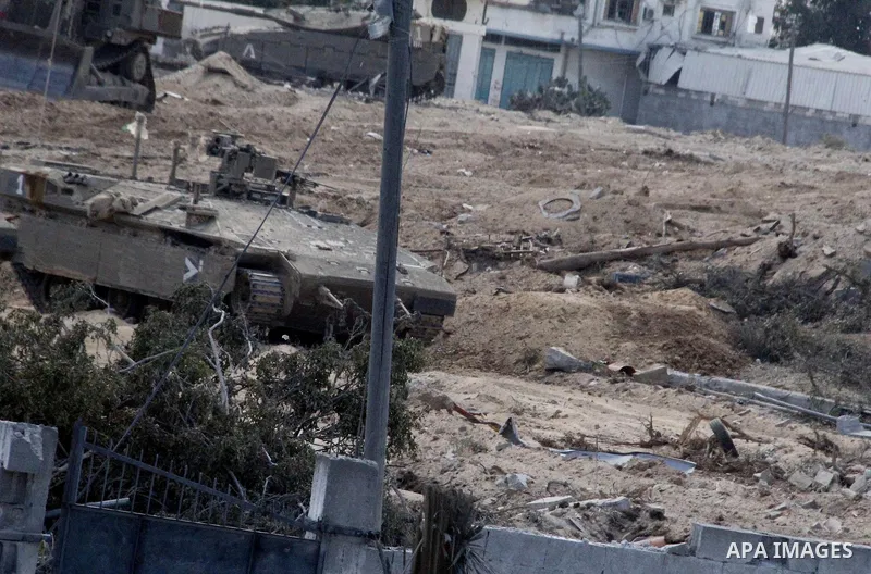 An Israeli military tank patrols amid of rubble of destroyed buildings at al-Shijaiyah district in the eastern Gaza City on July 26, 2014. Israeli troops remained in place across the Gaza Strip and continued to search fo...