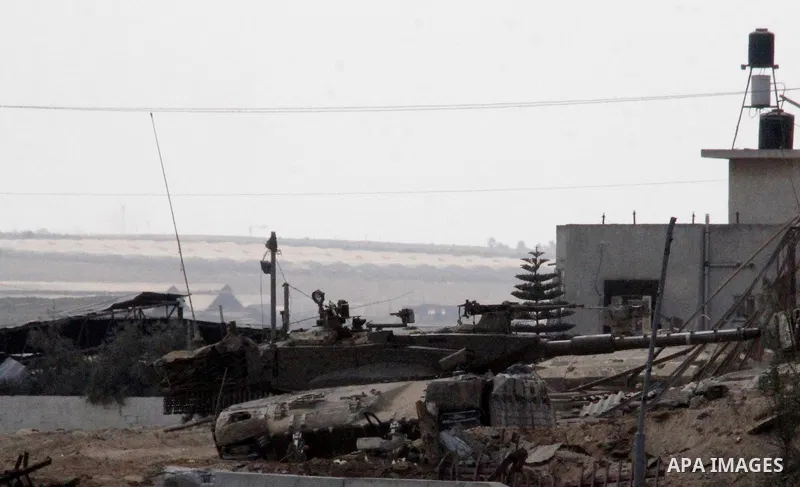 An Israeli military tank patrols amid of rubble of destroyed buildings at al-Shijaiyah district in the eastern Gaza City on July 26, 2014. Israeli troops remained in place across the Gaza Strip and continued to search fo...