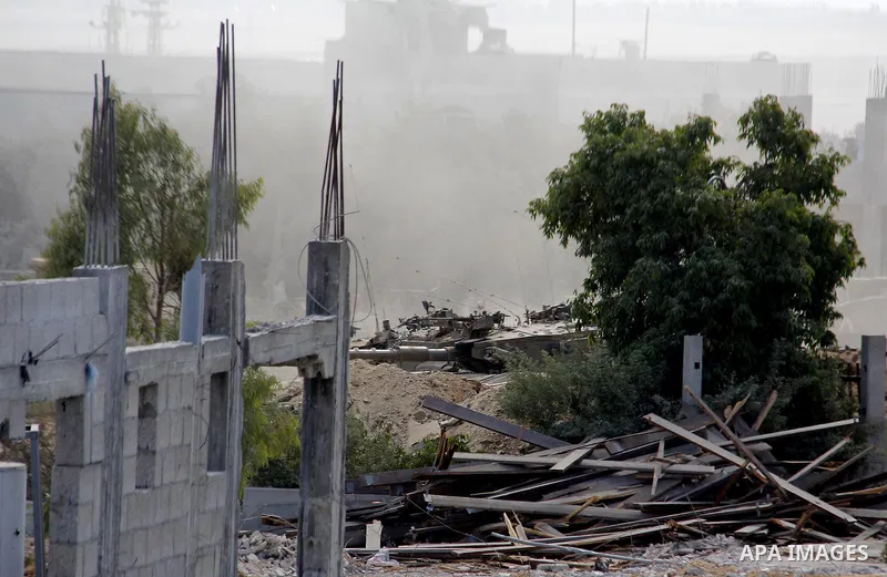 An Israeli military tank patrols amid of rubble of destroyed buildings at al-Shijaiyah district in the eastern Gaza City on July 26, 2014. Israeli troops remained in place across the Gaza Strip and continued to search fo...