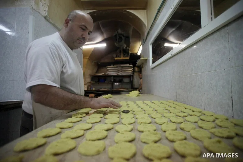 A Palestinian man prepares sweets for preparation for the upcoming Eid al-Fitr festival, at a market in Jerusalem on July 27, 2014. Eid al-Fitr festival is welcomed as a sad Eid between Palestinians as Israeli forces ren...