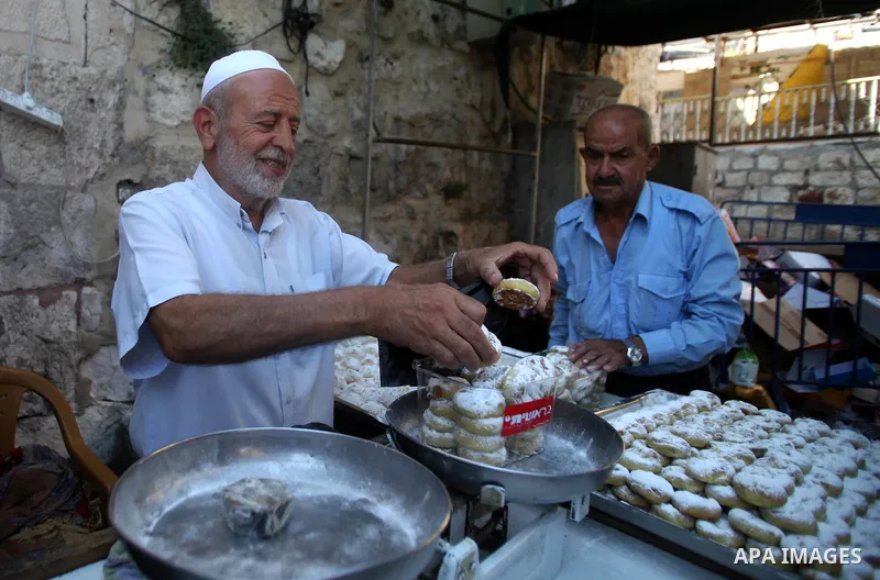 A Palestinian man sells sweets for preparation for the upcoming Eid al-Fitr festival, at a market in Jerusalem on July 27, 2014. Eid al-Fitr festival is welcomed as a sad Eid between Palestinians as Israeli forces renewe...