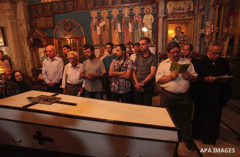 Palestinian relatives and friends of Jalila Ayad, a Christian woman whose body was found under the rubble of her home after an Israeli airstike, pray over her coffin during a religious service as part of her funeral on J...