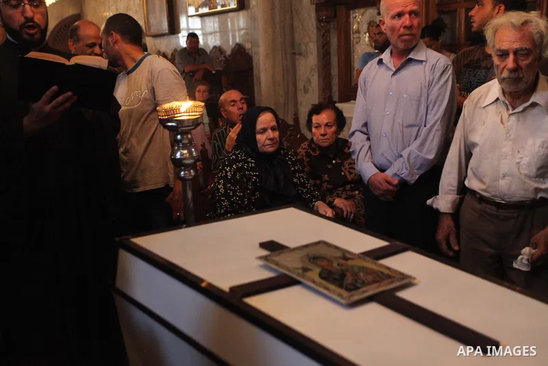 Palestinian relatives and friends of Jalila Ayad, a Christian woman whose body was found under the rubble of her home after an Israeli airstike, pray over her coffin during a religious service as part of her funeral on J...