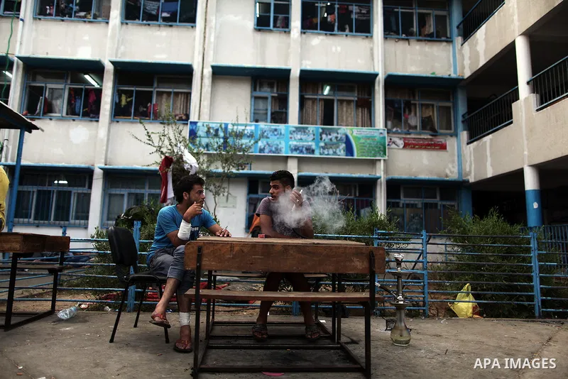 Displaced Palestinians smoke hookah during the celebration of Eid al-Fitr festival at a United Nations school, in Gaza City on July 28, 2014. The U.N. Security Council agreed on a statement on Sunday urging Israel, Pales...