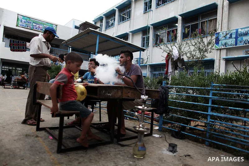 Displaced Palestinians smoke hookah during the celebration of Eid al-Fitr festival at a United Nations school, in Gaza City on July 28, 2014. The U.N. Security Council agreed on a statement on Sunday urging Israel, Pales...