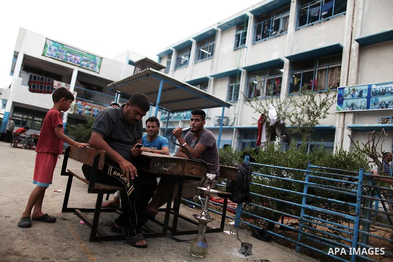 Displaced Palestinians smoke hookah during the celebration of Eid al-Fitr festival at a United Nations school, in Gaza City on July 28, 2014. The U.N. Security Council agreed on a statement on Sunday urging Israel, Pales...