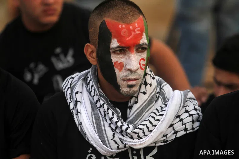 A Palestinian protester with national flag painted on his face takes part in a protest against the Israeli military operation on Gaza Strip following the Eid al-Fitr prayer, in the West Bank villages of Bilin, near Ramal...