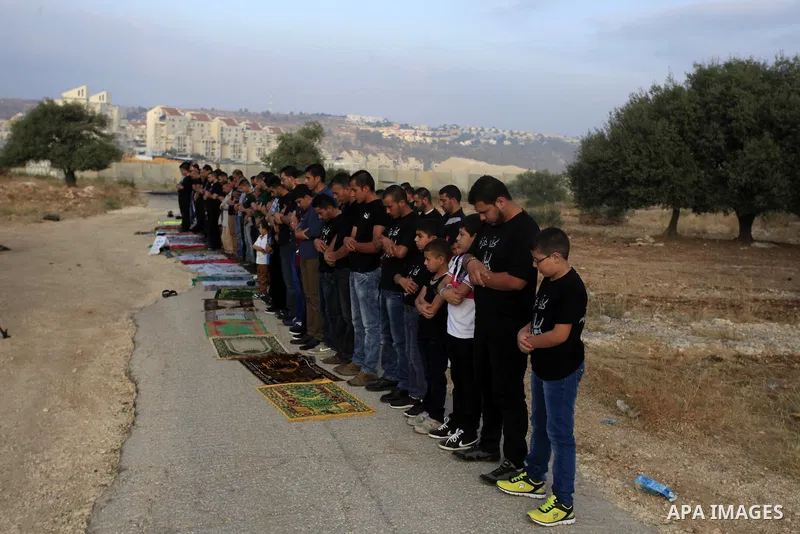 Palestinian protesters attend the Eid al-Fitr prayer during a protest against the Israeli military operation on Gaza Strip, in the West Bank villages of Bilin, near Ramallah on July 28, 2014. The U.N. Security Council ag...
