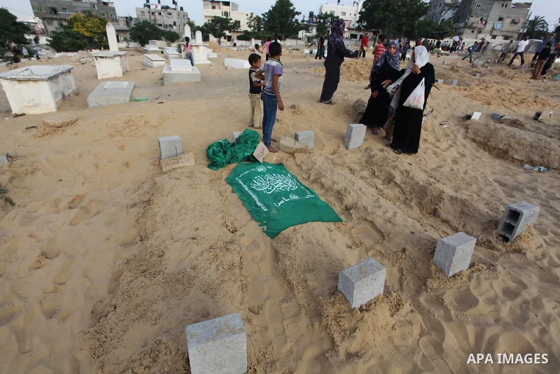 Palestinians mourn at the graves of their relatives, who medics said were killed during the Israeli offensive, during the Muslim holiday of Eid al-Fitr at a cemetery in Beit Lahiyah in the northern Gaza Strip July 28, 20...