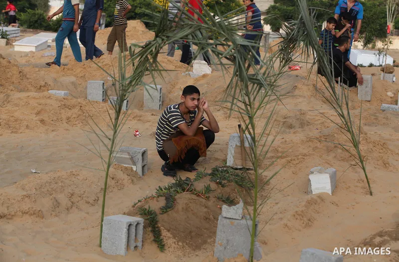 A Palestinian boy mourns next to his brother's grave, who medics said was killed during the Israeli offensive, during the Muslim holiday of Eid al-Fitr at a cemetery in Beit Lahiyah in the northern Gaza Strip July 28, 20...