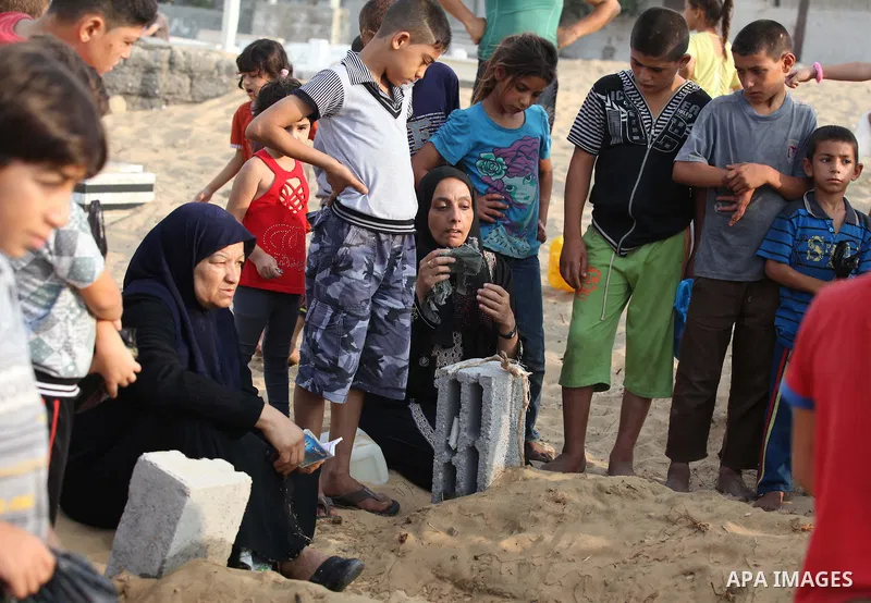 Palestinians mourn at the graves of their relatives, who medics said were killed during the Israeli offensive, during the Muslim holiday of Eid al-Fitr at a cemetery in Beit Lahiyah in the northern Gaza Strip July 28, 20...
