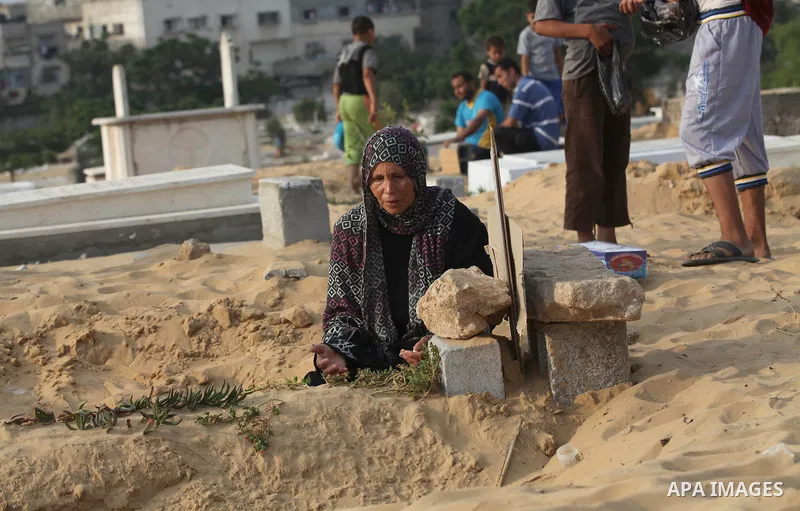 Palestinians mourn at the graves of their relatives, who medics said were killed during the Israeli offensive, during the Muslim holiday of Eid al-Fitr at a cemetery in Beit Lahiyah in the northern Gaza Strip July 28, 20...