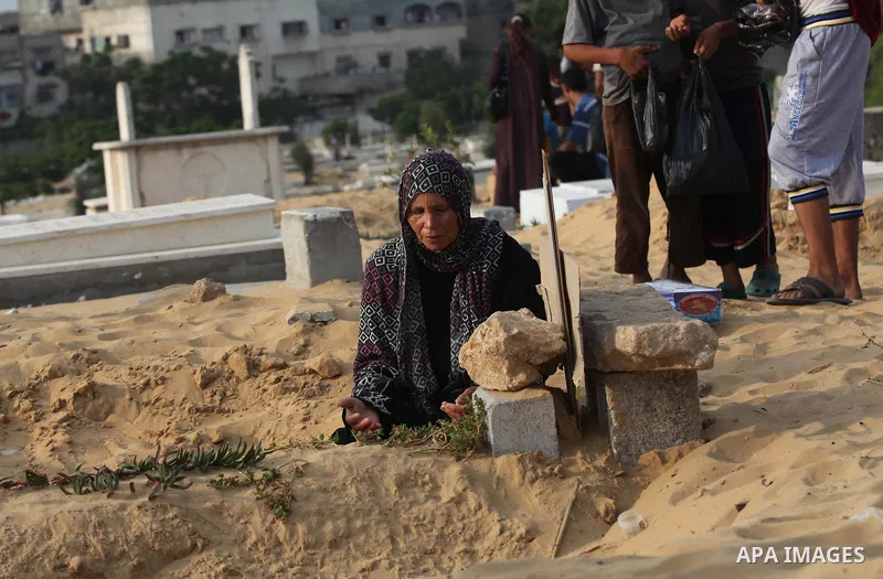 Palestinians mourn at the graves of their relatives, who medics said were killed during the Israeli offensive, during the Muslim holiday of Eid al-Fitr at a cemetery in Beit Lahiyah in the northern Gaza Strip July 28, 20...