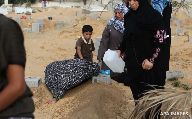 Palestinians mourn at the graves of their relatives, who medics said were killed during the Israeli offensive, during the Muslim holiday of Eid al-Fitr at a cemetery in Beit Lahiyah in the northern Gaza Strip July 28, 20...