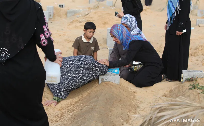 Palestinians mourn at the graves of their relatives, who medics said were killed during the Israeli offensive, during the Muslim holiday of Eid al-Fitr at a cemetery in Beit Lahiyah in the northern Gaza Strip July 28, 20...