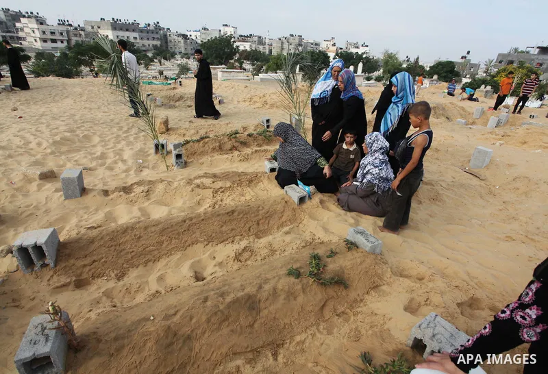 Palestinians mourn at the graves of their relatives, who medics said were killed during the Israeli offensive, during the Muslim holiday of Eid al-Fitr at a cemetery in Beit Lahiyah in the northern Gaza Strip July 28, 20...