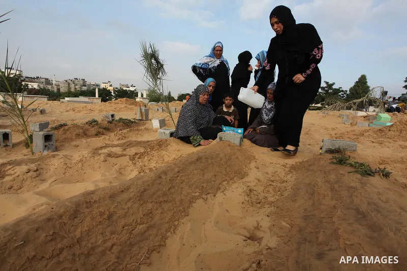 Palestinians mourn at the graves of their relatives, who medics said were killed during the Israeli offensive, during the Muslim holiday of Eid al-Fitr at a cemetery in Beit Lahiyah in the northern Gaza Strip July 28, 20...
