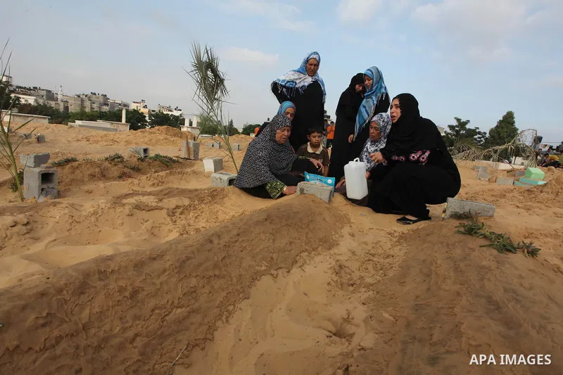 Palestinians mourn at the graves of their relatives, who medics said were killed during the Israeli offensive, during the Muslim holiday of Eid al-Fitr at a cemetery in Beit Lahiyah in the northern Gaza Strip July 28, 20...