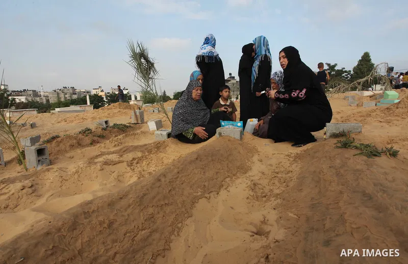 Palestinians mourn at the graves of their relatives, who medics said were killed during the Israeli offensive, during the Muslim holiday of Eid al-Fitr at a cemetery in Beit Lahiyah in the northern Gaza Strip July 28, 20...