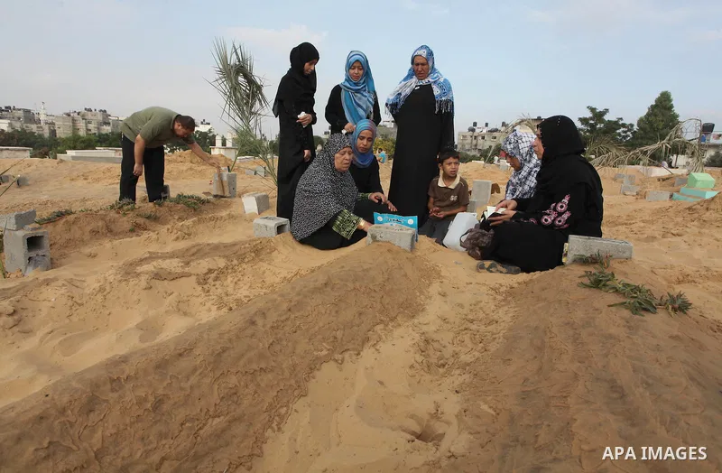 Palestinians mourn at the graves of their relatives, who medics said were killed during the Israeli offensive, during the Muslim holiday of Eid al-Fitr at a cemetery in Beit Lahiyah in the northern Gaza Strip July 28, 20...