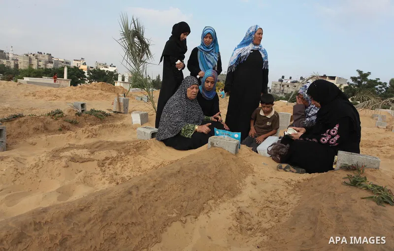 Palestinians mourn at the graves of their relatives, who medics said were killed during the Israeli offensive, during the Muslim holiday of Eid al-Fitr at a cemetery in Beit Lahiyah in the northern Gaza Strip July 28, 20...