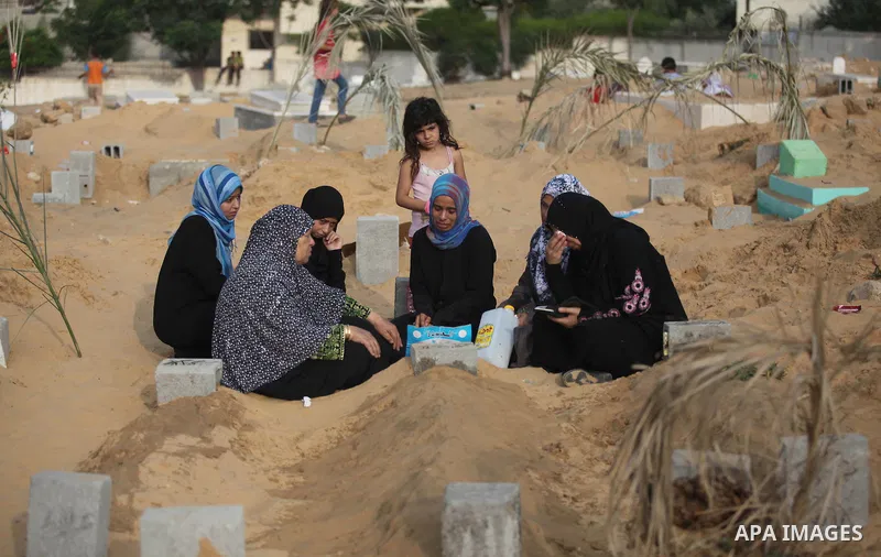 Palestinians mourn at the graves of their relatives, who medics said were killed during the Israeli offensive, during the Muslim holiday of Eid al-Fitr at a cemetery in Beit Lahiyah in the northern Gaza Strip July 28, 20...