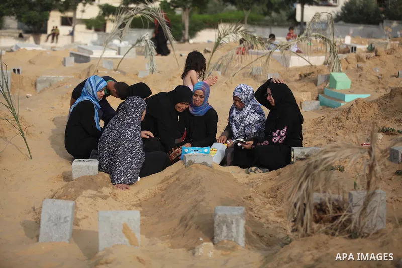 Palestinians mourn at the graves of their relatives, who medics said were killed during the Israeli offensive, during the Muslim holiday of Eid al-Fitr at a cemetery in Beit Lahiyah in the northern Gaza Strip July 28, 20...