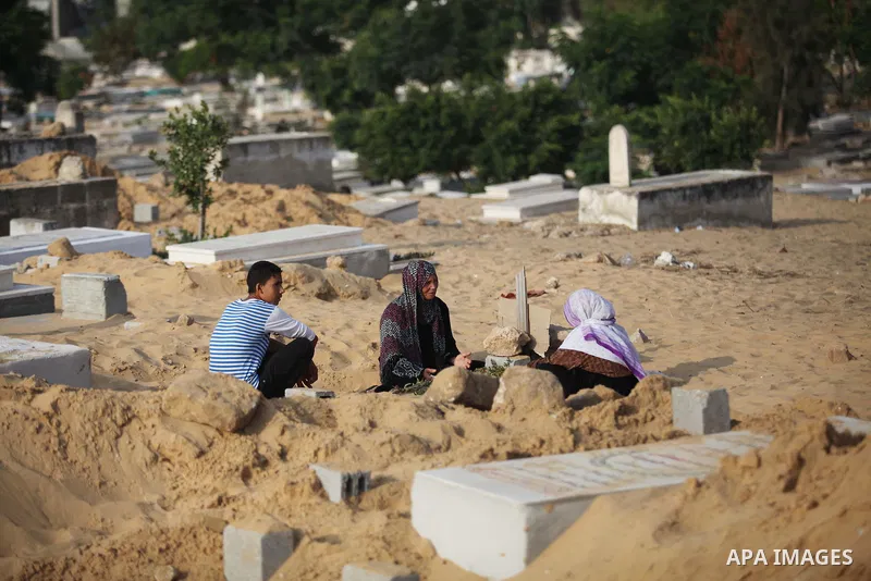 Palestinians mourn at the graves of their relatives, who medics said were killed during the Israeli offensive, during the Muslim holiday of Eid al-Fitr at a cemetery in Beit Lahiyah in the northern Gaza Strip July 28, 20...