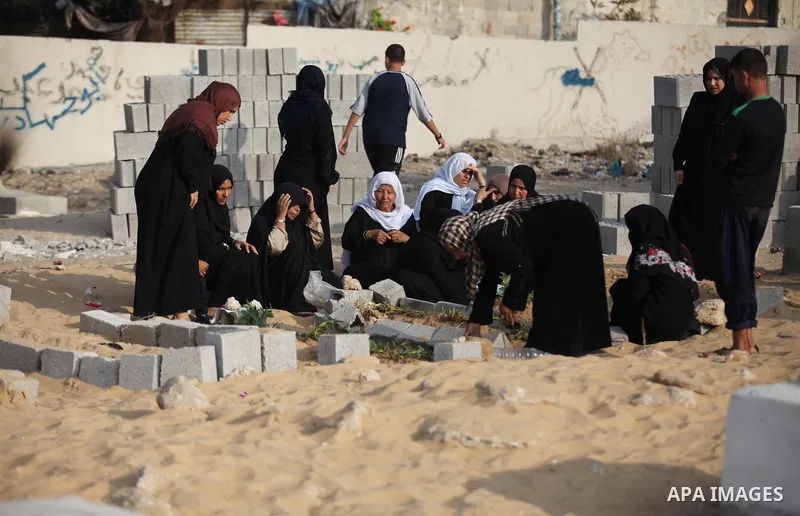 Palestinians mourn at the graves of their relatives, who medics said were killed during the Israeli offensive, during the Muslim holiday of Eid al-Fitr at a cemetery in Beit Lahiyah in the northern Gaza Strip July 28, 20...