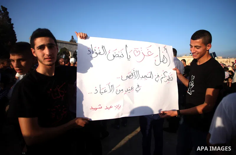 Palestinian protesters hold a placard during a protest against the Israeli military operation on Gaza Strip following the Eid al-Fitr prayer at al-Aqsa mosque in Jerusalem's Old City on July 28, 2014. Muslims around the...