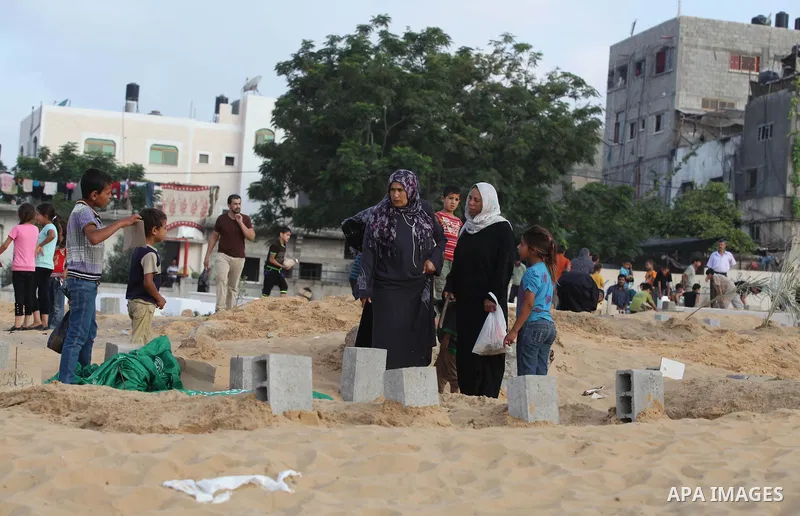 Palestinians mourn at the graves of their relatives, who medics said were killed during the Israeli offensive, during the Muslim holiday of Eid al-Fitr at a cemetery in Beit Lahiyah in the northern Gaza Strip July 28, 20...