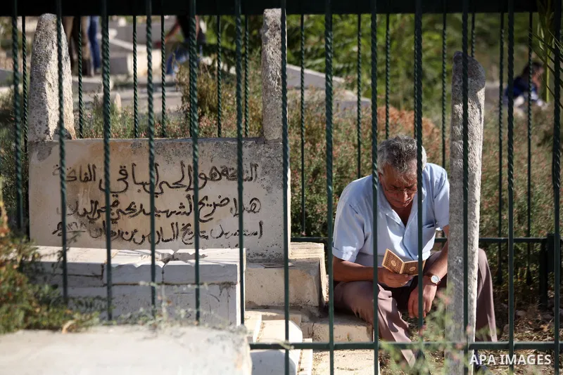 A Palestinian man prays on the grave of their relative in a cemetery during Eid al-Fitr celebrations, in Jerusalem's Old City on July 28, 2014. Muslims around the world are celebrating Eid al-Fitr which marks the end of...