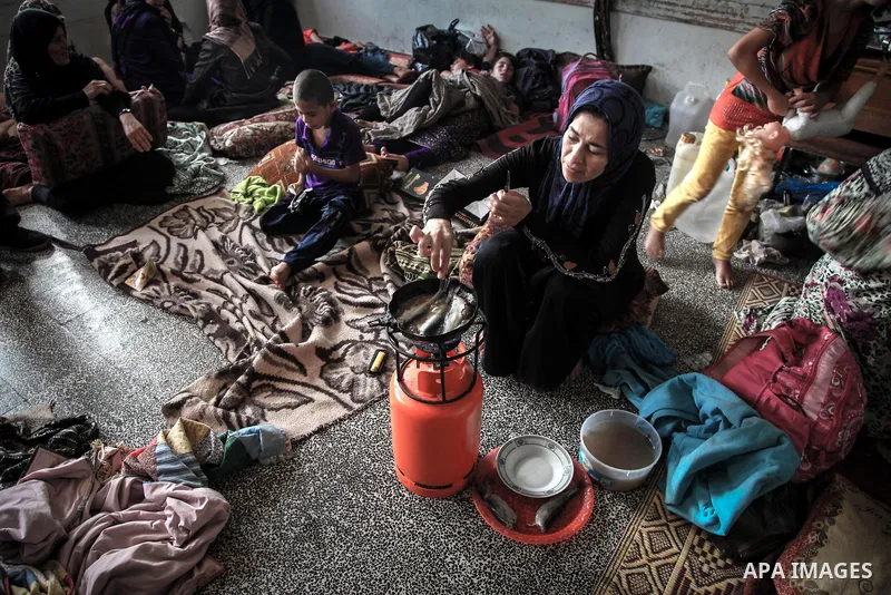 A displaced Palestinian woman cooks in a room at an United Nations (UN) school in Jabalia in the northern Gaza Strip, where her family found refugee after fleeing their home in an area under heavy Israeli bombardment in...