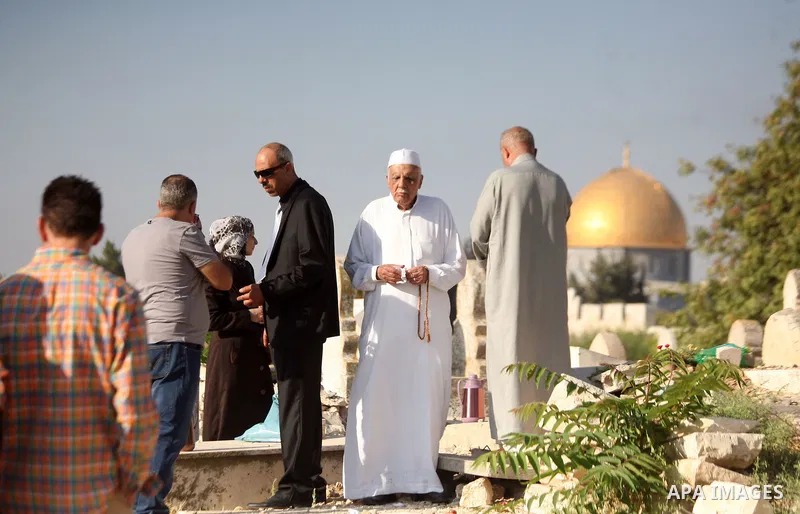 Palestinians visit the graves of their relatives in a cemetery during Eid al-Fitr celebrations, in Jerusalem's Old City on July 28, 2014. Muslims around the world are celebrating Eid al-Fitr which marks the end of the mo...