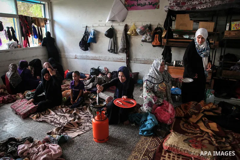 A displaced Palestinian woman cooks in a room at an United Nations (UN) school in Jabalia in the northern Gaza Strip, where her family found refugee after fleeing their home in an area under heavy Israeli bombardment in...
