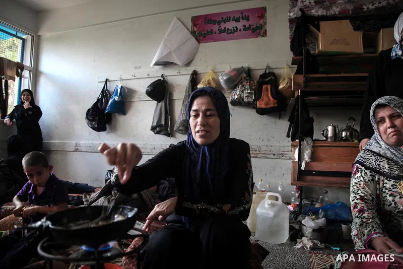A displaced Palestinian woman cooks in a room at an United Nations (UN) school in Jabalia in the northern Gaza Strip, where her family found refugee after fleeing their home in an area under heavy Israeli bombardment in...