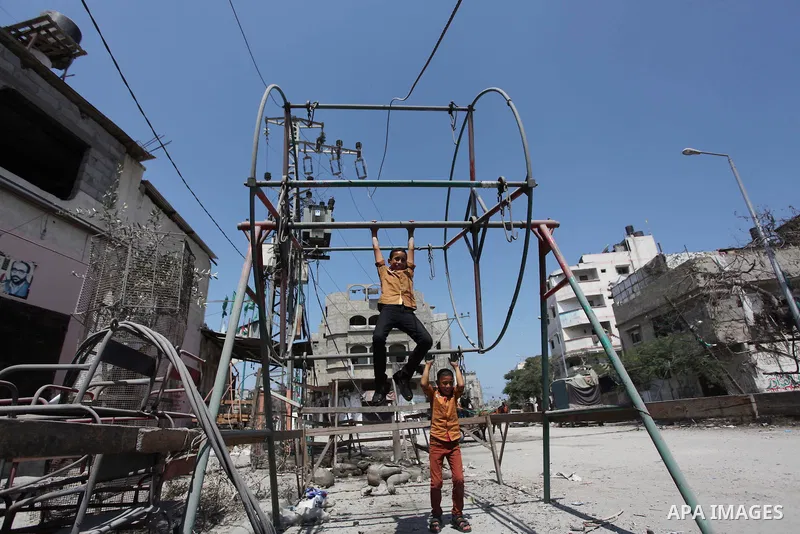 Palestinian children play near a damaged mini ferris wheel in the wartorn Shejaiya district of Gaza City on July 28, 2014 on the first day of Eid al-Fitr holiday. The Muslim three-day Eid al-Fitr festival, that marks the...