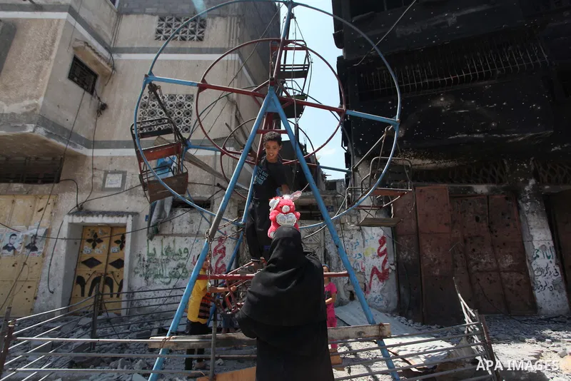 Palestinian children play near a damaged mini ferris wheel in the wartorn Shejaiya district of Gaza City on July 28, 2014 on the first day of Eid al-Fitr holiday. The Muslim three-day Eid al-Fitr festival, that marks the...