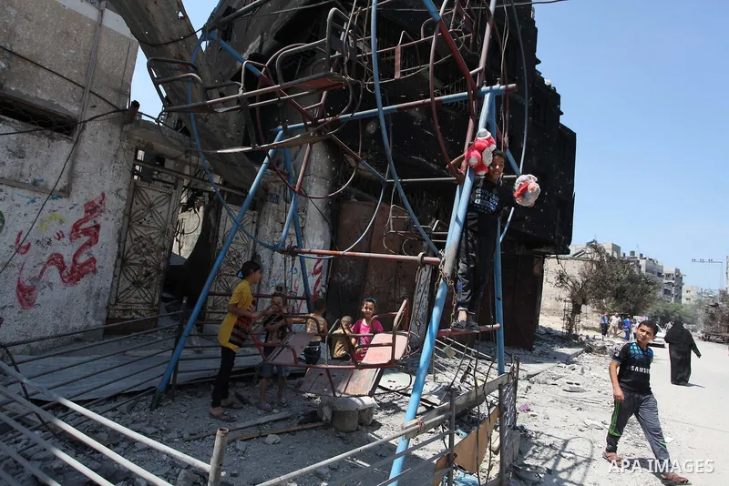 Palestinian children play near a damaged mini ferris wheel in the wartorn Shejaiya district of Gaza City on July 28, 2014 on the first day of Eid al-Fitr holiday. The Muslim three-day Eid al-Fitr festival, that marks the...
