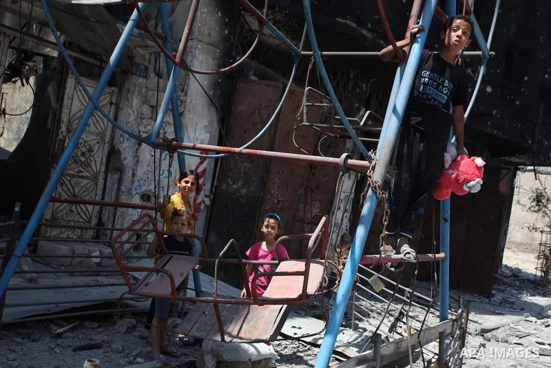 Palestinian children play near a damaged mini ferris wheel in the wartorn Shejaiya district of Gaza City on July 28, 2014 on the first day of Eid al-Fitr holiday. The Muslim three-day Eid al-Fitr festival, that marks the...